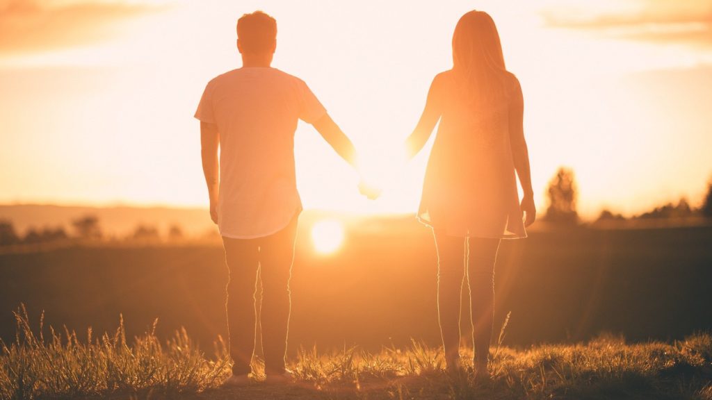 couple qui se tient face à un coucher de soleil