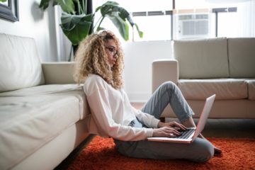 femme blonde blouckée devant son pc sur le sol du salon